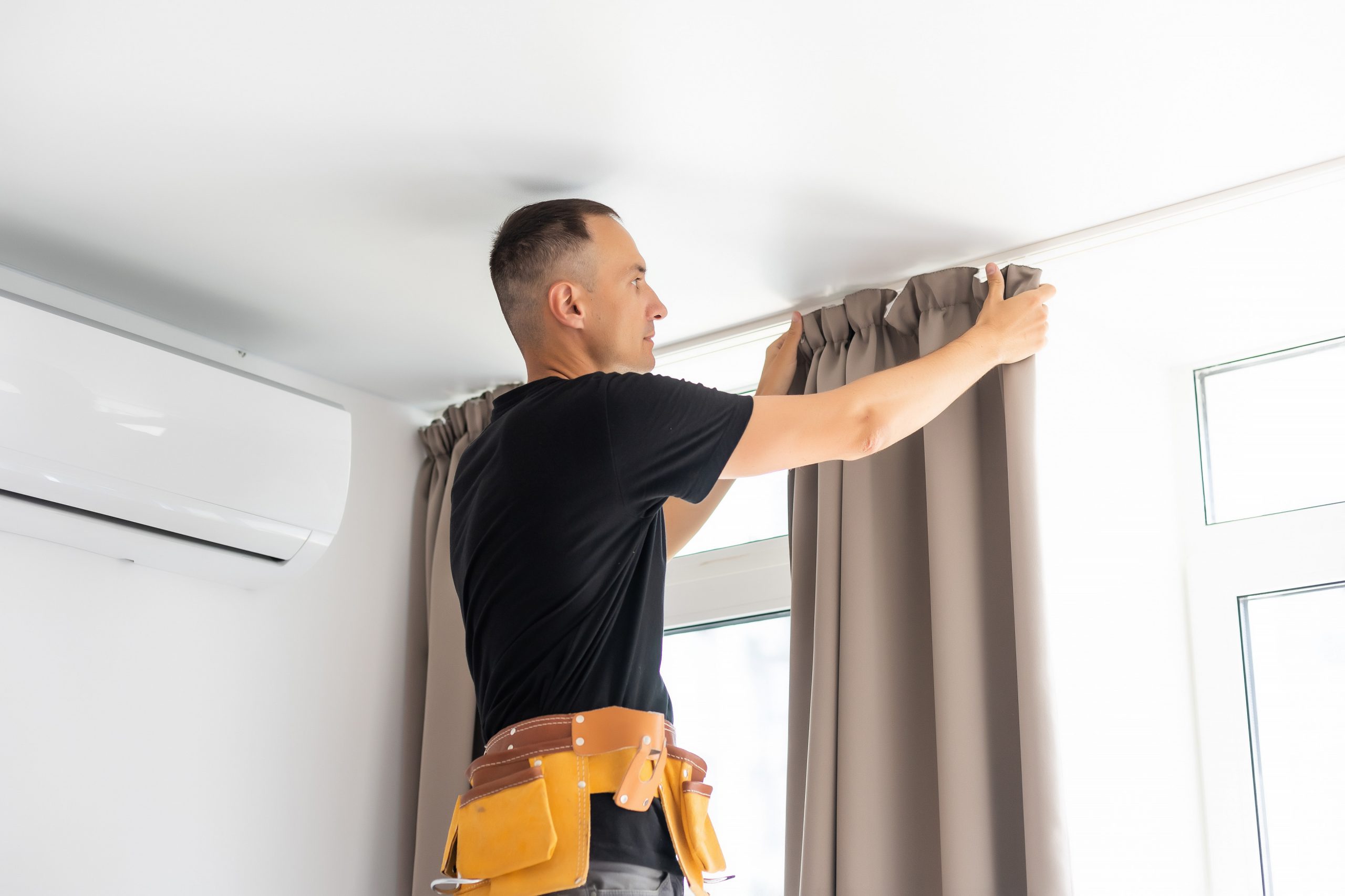 worker repairman hanging and fixing the curtain on the window